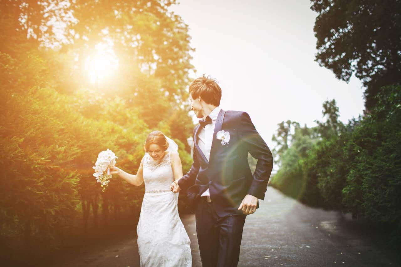 hochzeitsrausch Brautmoden - Brautkleid mit Spitze und Braeutigam-Anzug bei Sonnenuntergang im Garten