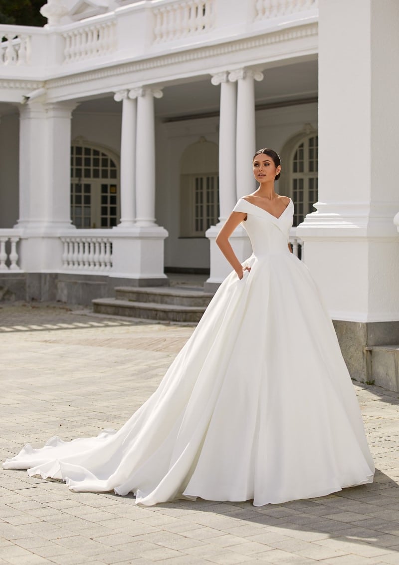 hochzeitsrausch Brautmoden - Elegantes Brautkleid mit Off-Shoulder-Design vor klassischer Architektur