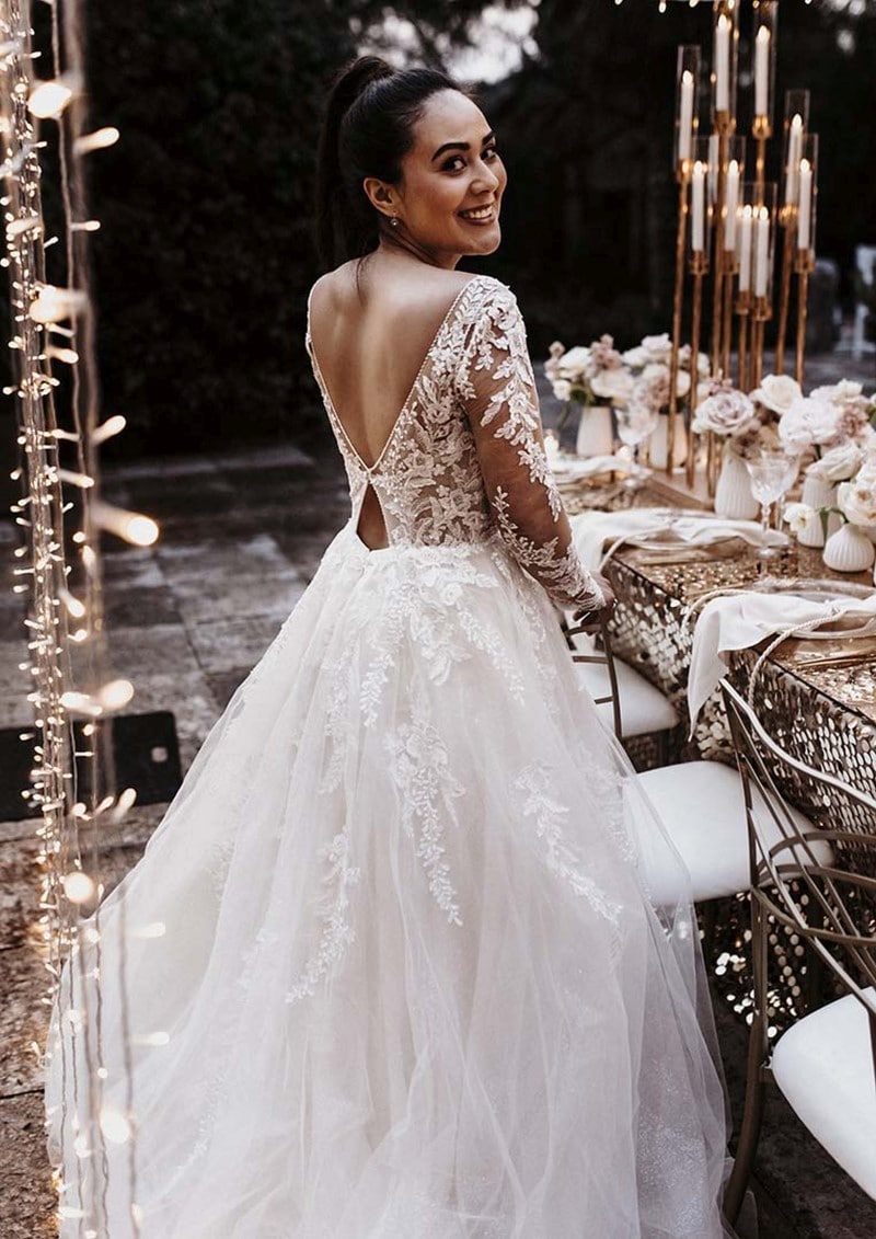 hochzeitsrausch Brautmoden - Elegantes Brautkleid mit Spitzenärmeln und tiefem Rückenausschnitt bei romantischer Hochzeitsfeier