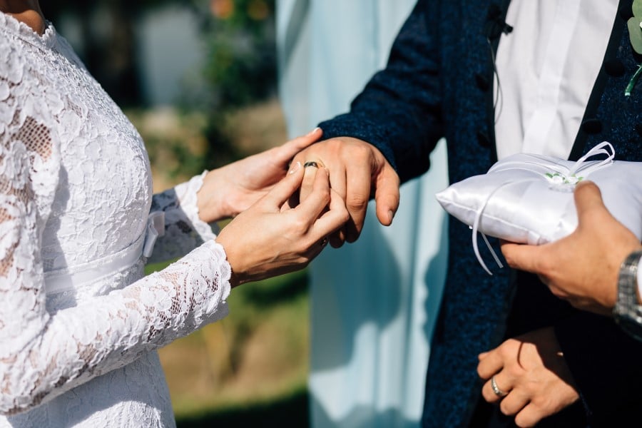 hochzeitsrausch Brautmoden - Austausch von Eheringen bei Hochzeit, Braut in Spitzenkleid, Braeutigam im Anzug