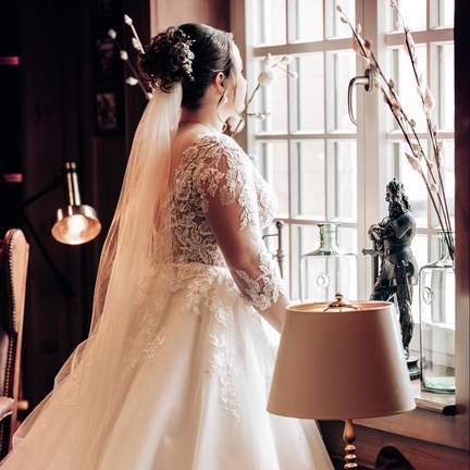 hochzeitsrausch Brautmoden - Brautkleid mit Spitzenärmeln und langem Schleier in romantischem Ambiente