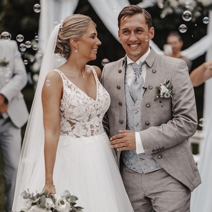 hochzeitsrausch Brautmoden - Brautkleid mit Spitzen und Braeutigam-Anzug in Grau, festliche Hochzeit im Freien