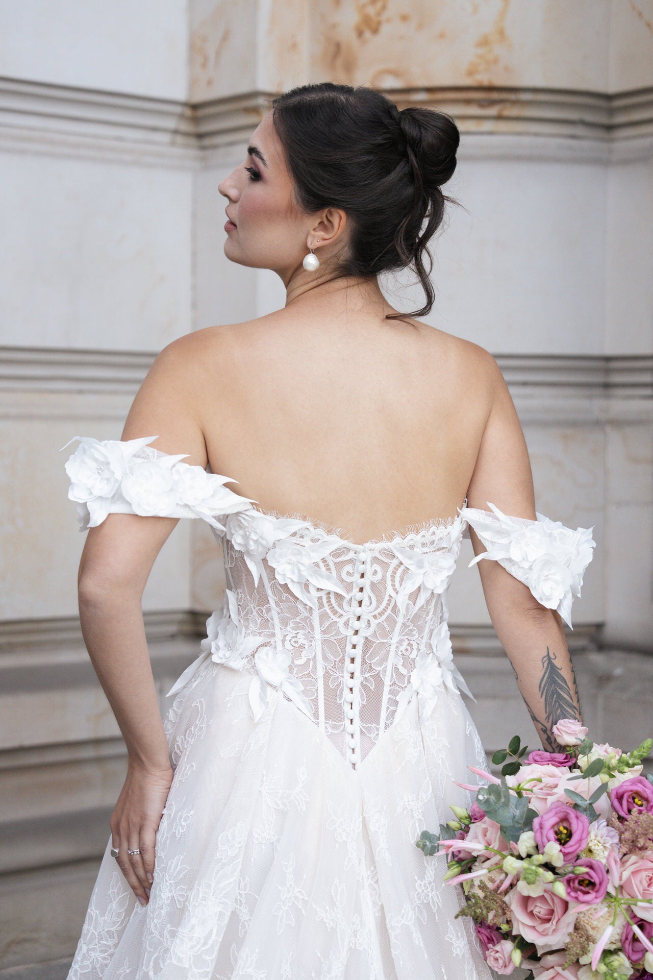 hochzeitsrausch Brautmoden - Brautkleid mit floralen Details und Spitzenrücken, romantische Stimmung mit Blumenstrauß