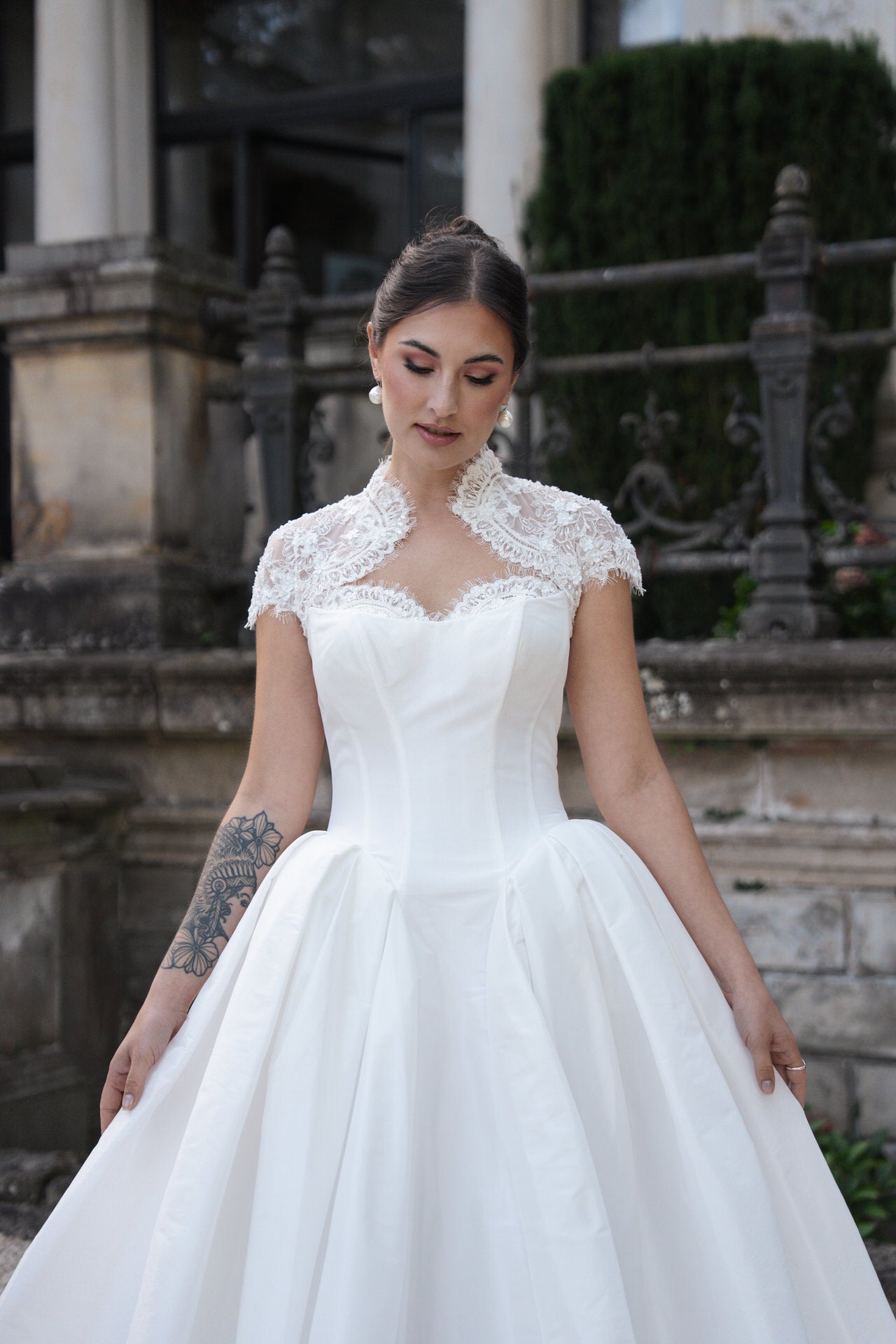 hochzeitsrausch Brautmoden - Elegantes Brautkleid mit Spitzenbolero und voluminösem Rock vor historischer Kulisse