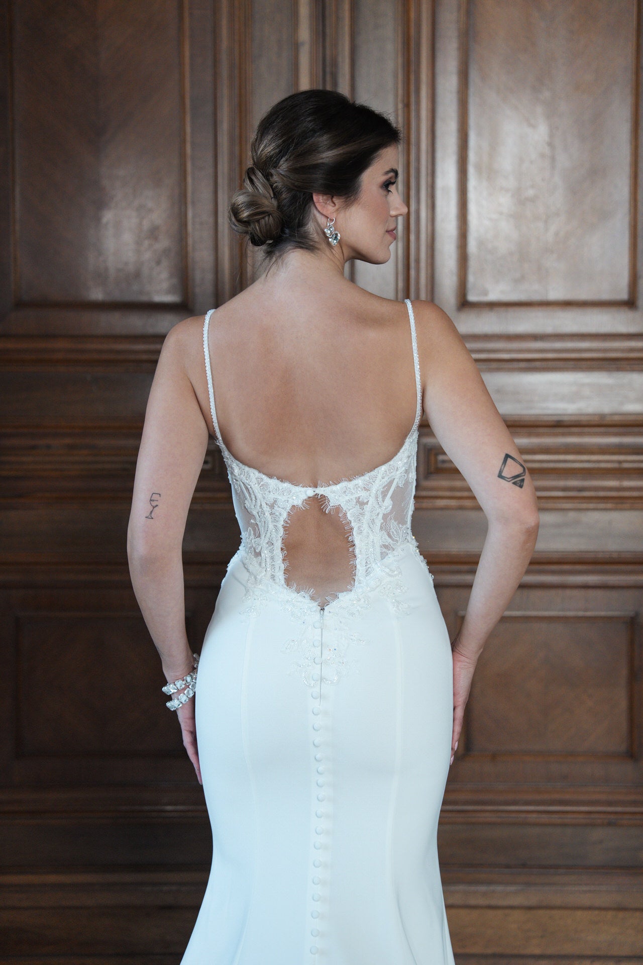 hochzeitsrausch Brautmoden - Elegantes Brautkleid mit Spitzenrücken und Knopfleiste vor Holzvertäfelung