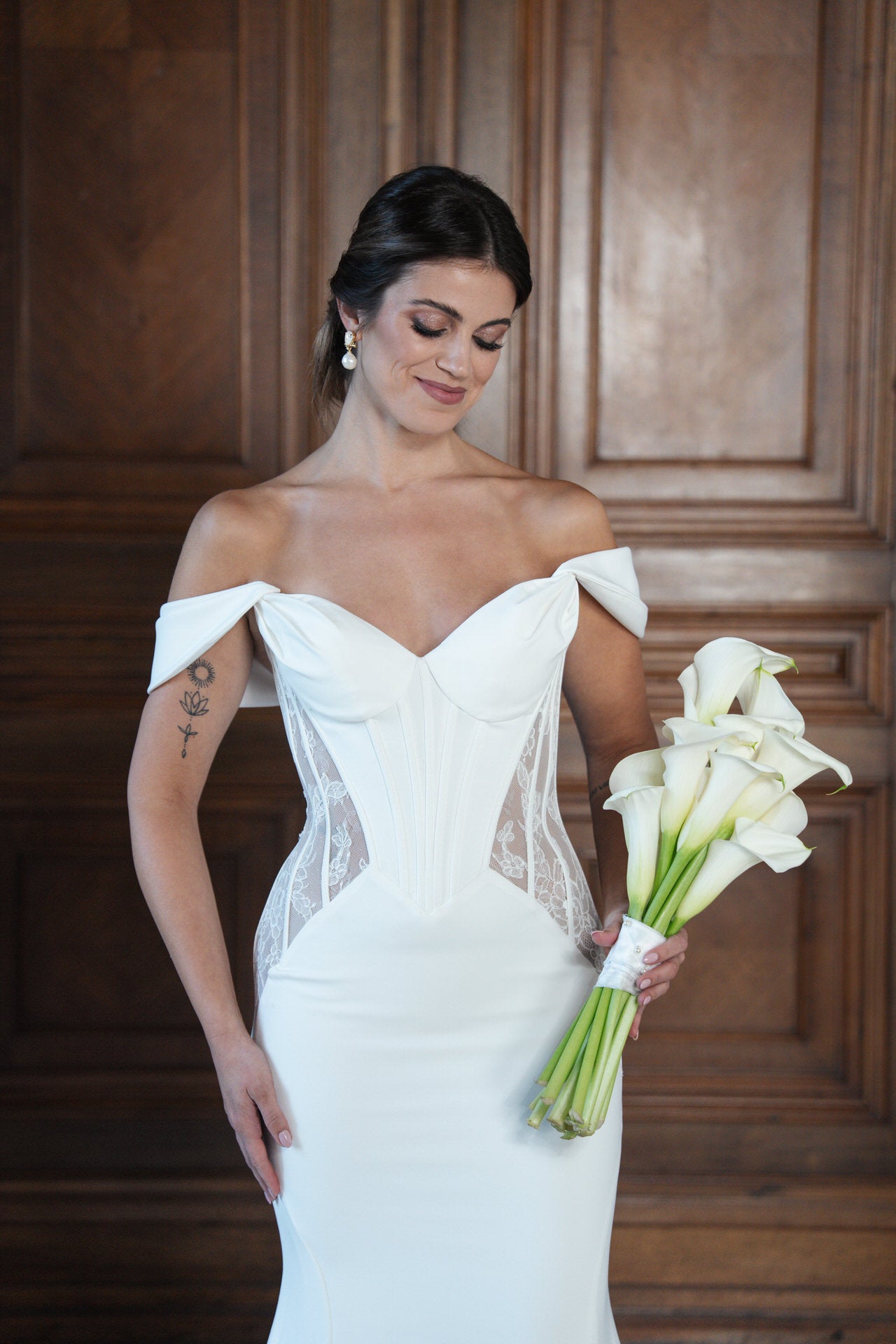 hochzeitsrausch Brautmoden - Elegantes Brautkleid mit schulterfreiem Design und Spitzenakzenten, Braut mit Blumenstrauß
