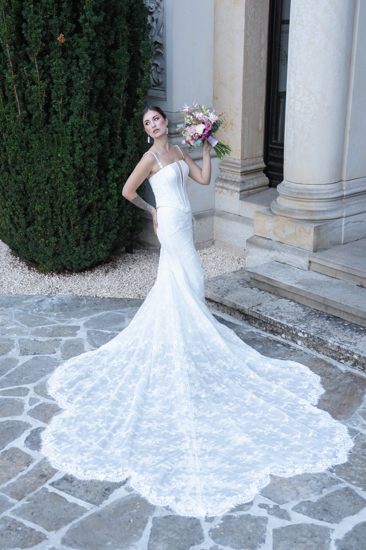 hochzeitsrausch Brautmoden - Elegantes Brautkleid mit langer Schleppe und floralen Details vor klassischer Kulisse